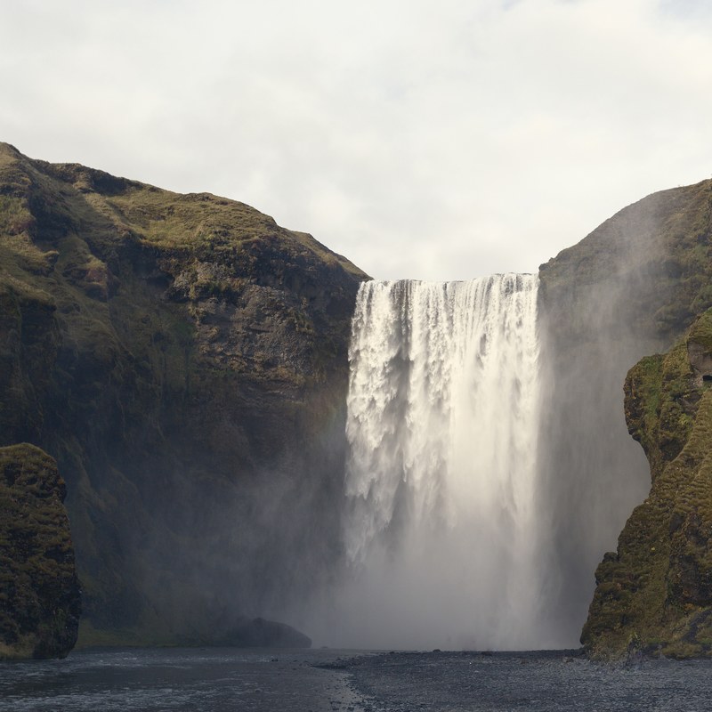 a large waterfall streaming from a rocky mountain in iceland, waterfalls in iceland 4k