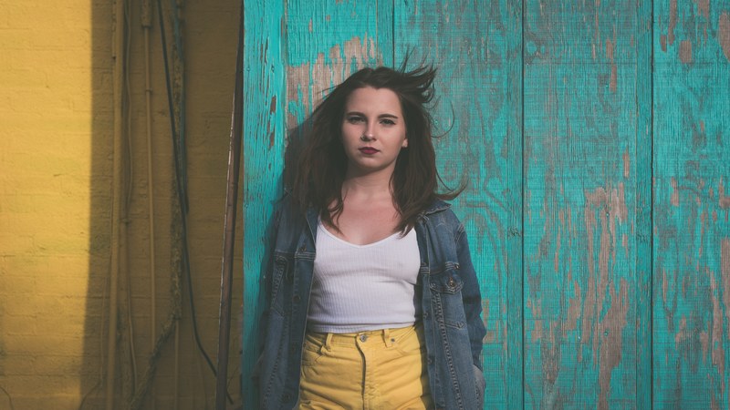 young woman in jeans jacket posing in front of colorful background at jacksonville beach, haley 4k