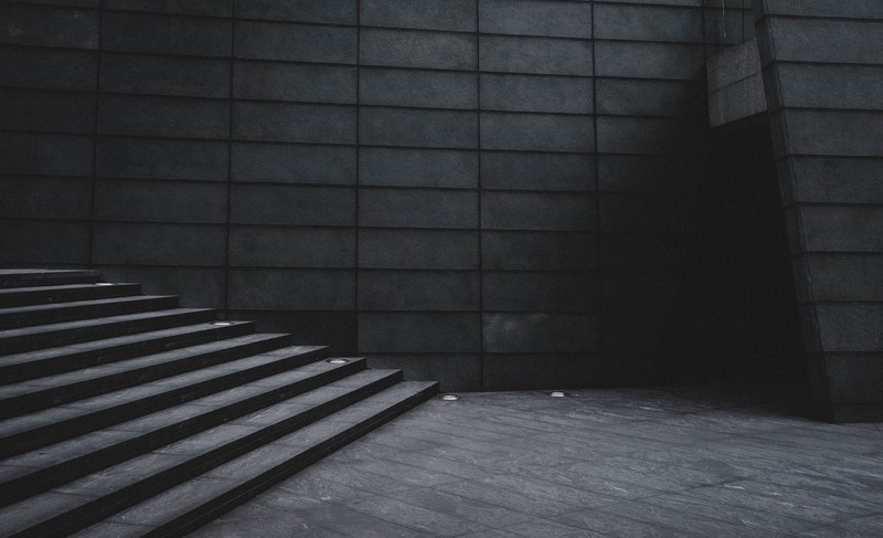 a dim shot of the bottom of a gray staircase in a concrete building, gloomy staircase 4k