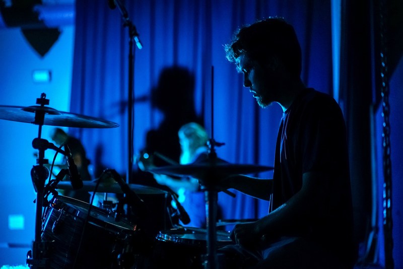 a man with a beard playing the drums in a room lit with a blue light, blue drums 4k