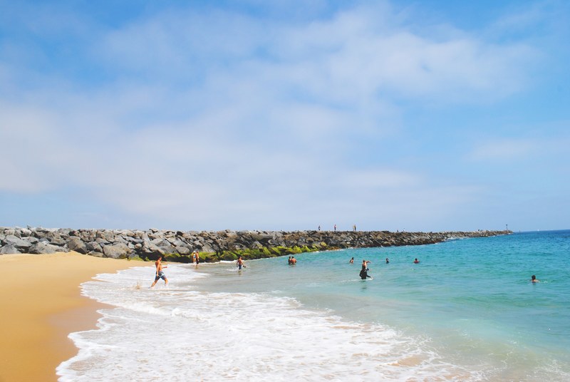 people enjoying and swimming in the ocean with side rocks during summer holiday in newport beach, sumer holiday in newport beach 4k