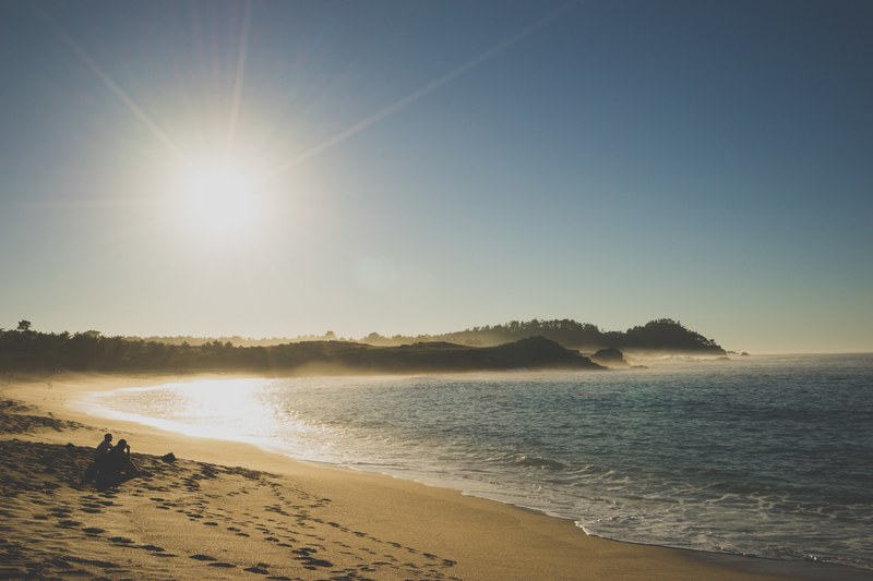 two buddies sit on beach shore in the midst of footprints at sunset, sitting on a beach around footprints 4k