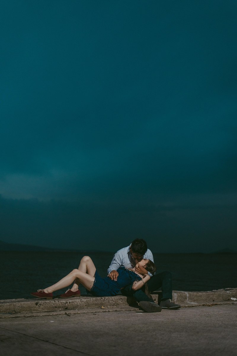 a couple is embracing and kissing on the sidewalk by the sea, _storm 4k