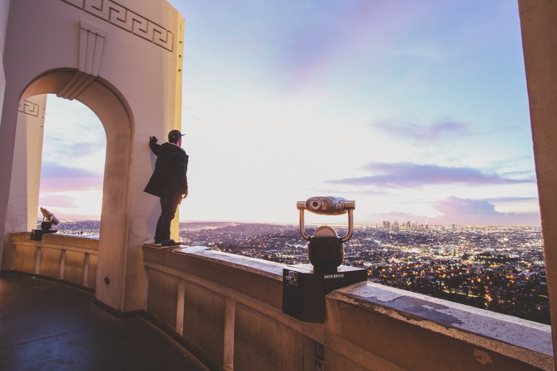 man stands on the ledge of a lookout point in the city, los angeles expedition 4k