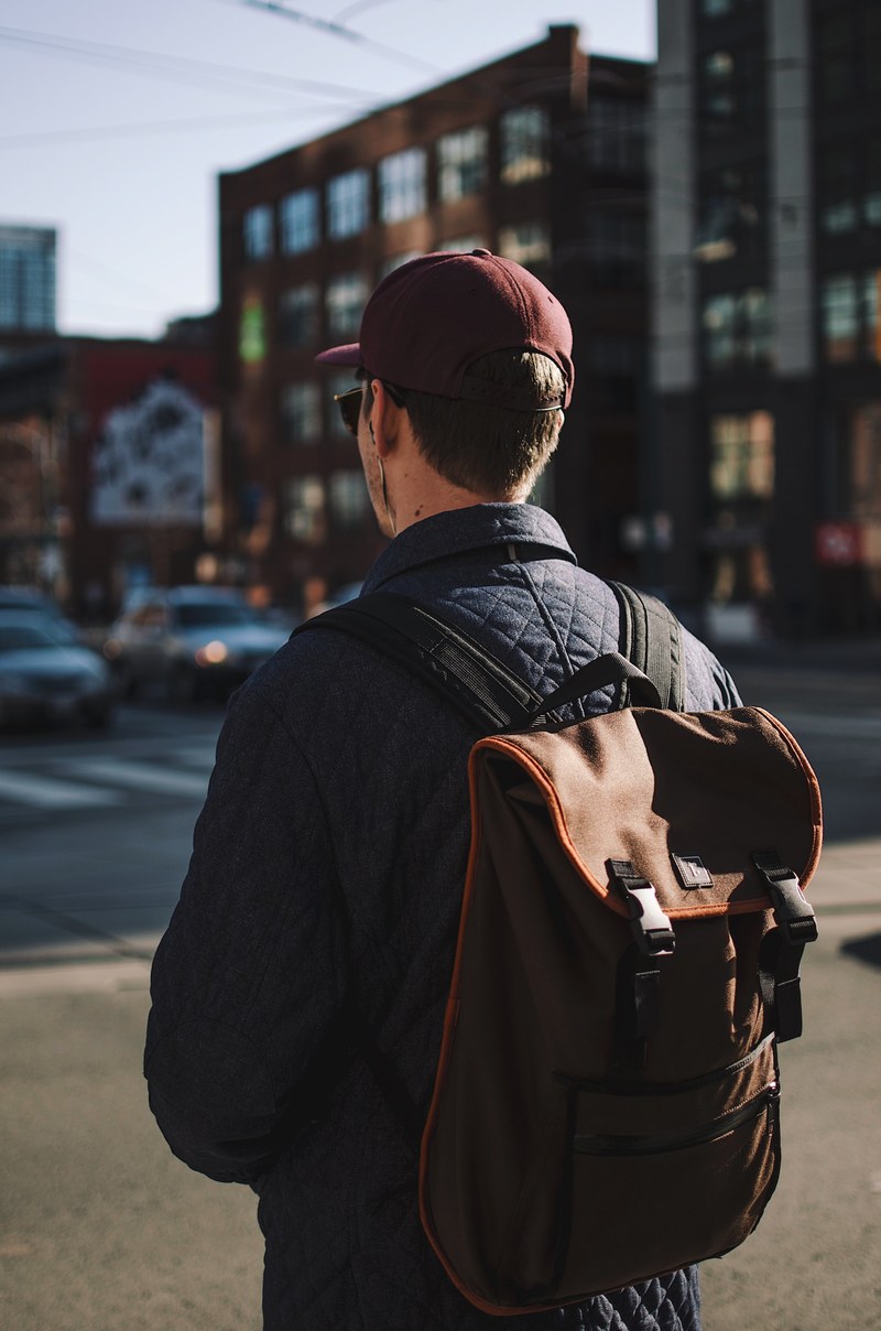 a man walking down a toronto street with a backpack and baseball hat on, parts unknown 4k