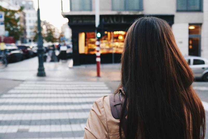 walking behind a woman about to cross a city street, crossing the street 4k
