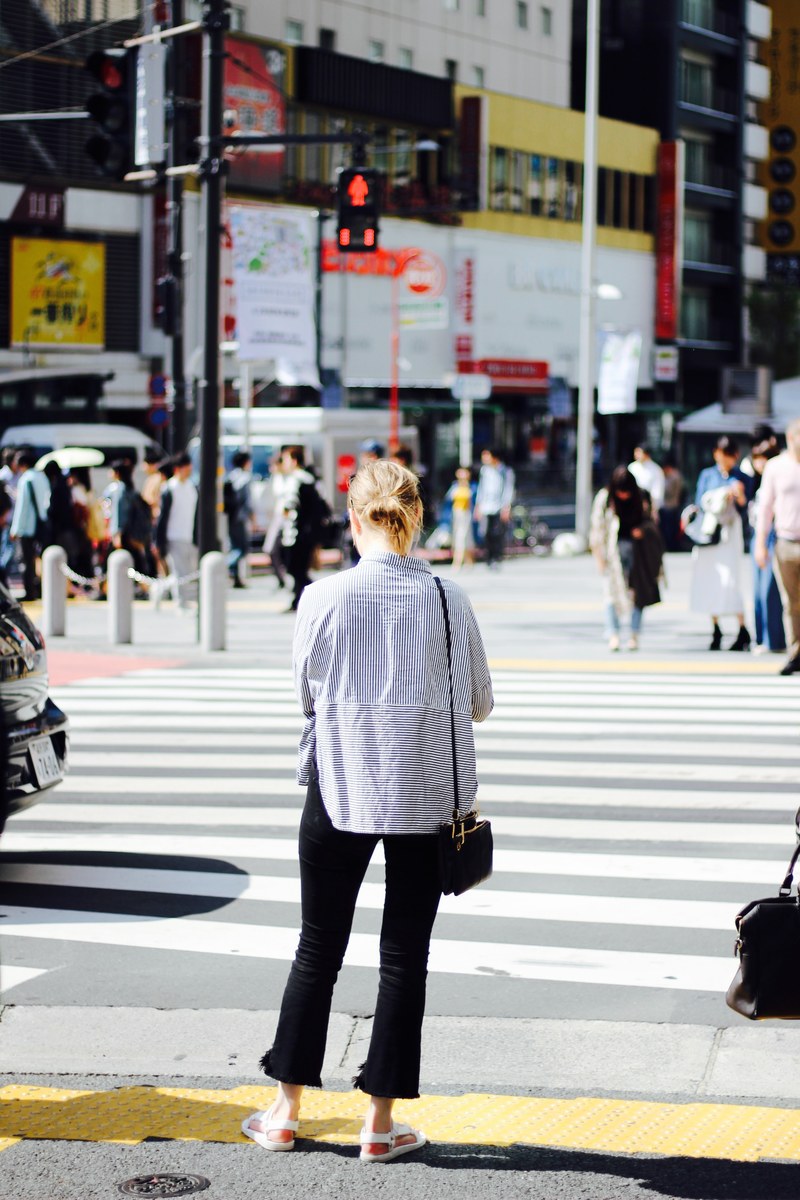a woman is waiting at the crosswalk for the lights to turn green in shibuya, _lost in translation 4k