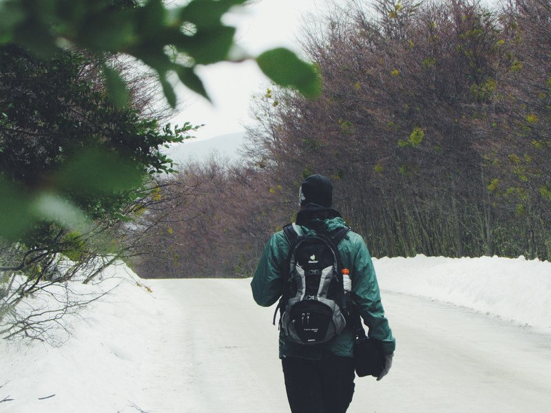 a person in a coat faces away while hiking on a snowy path in patagonia, mochileiro 4k