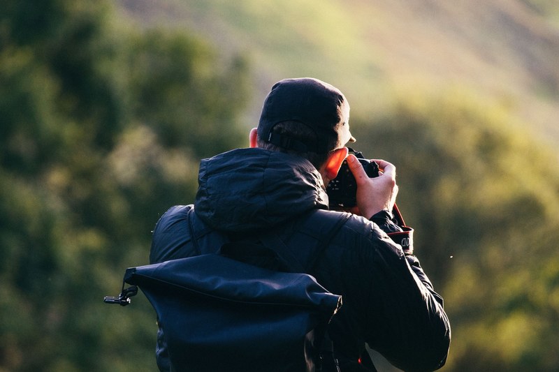 a man taking a picture of grassy mountains in snowdon wales, snowdon landscape photography 4k