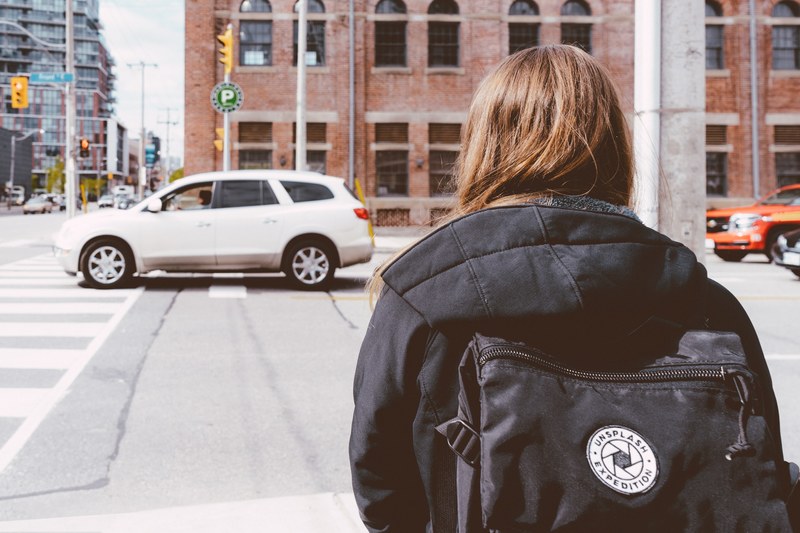 a woman with a black backpack waiting to cross the street in toronto, unsplash backpack 4k