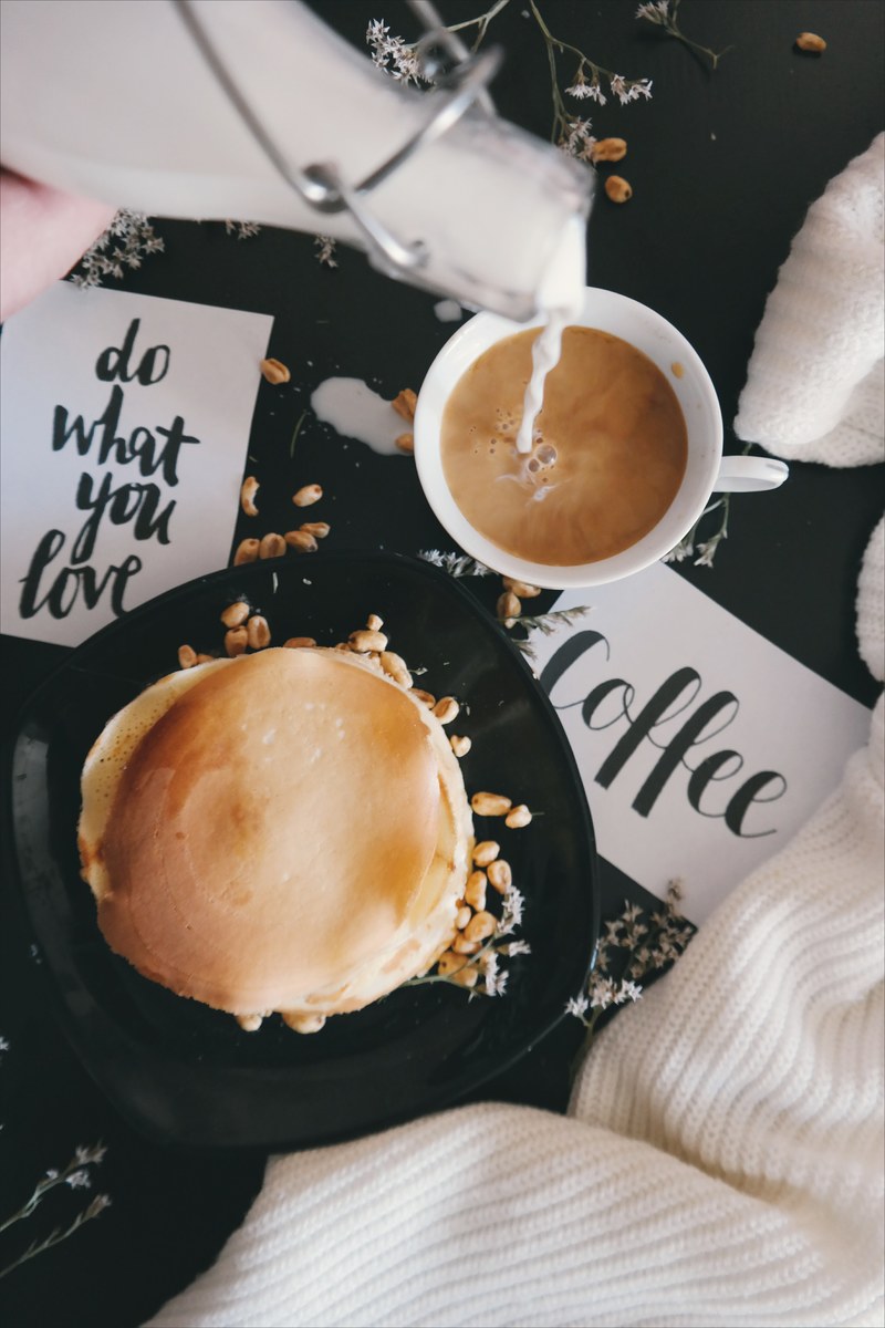 a plate of food with a cup of coffee taken while someone pours sugar into the drink, _coffee with pancakes 4k