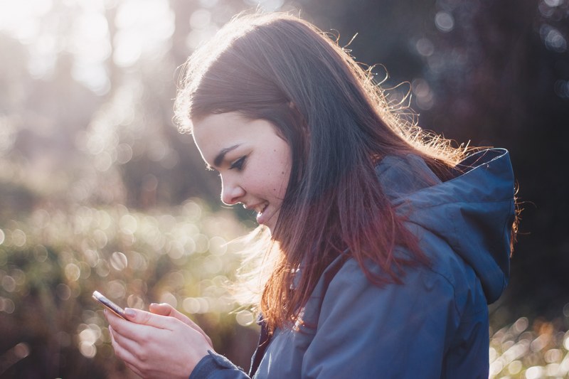 a young woman smiling while looking at a smartphone, woman smiling at a smartphone 4k