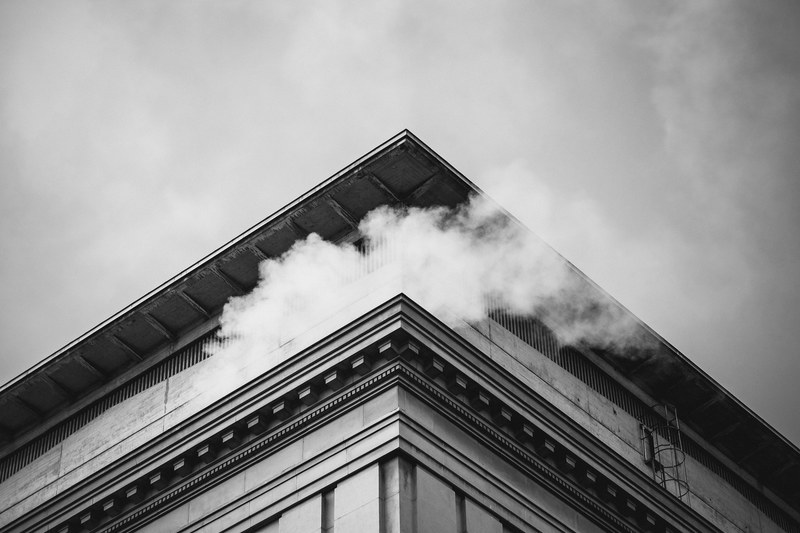 black and white shot of building roof corner with white smoke coming from top, building corner and smoke 4k