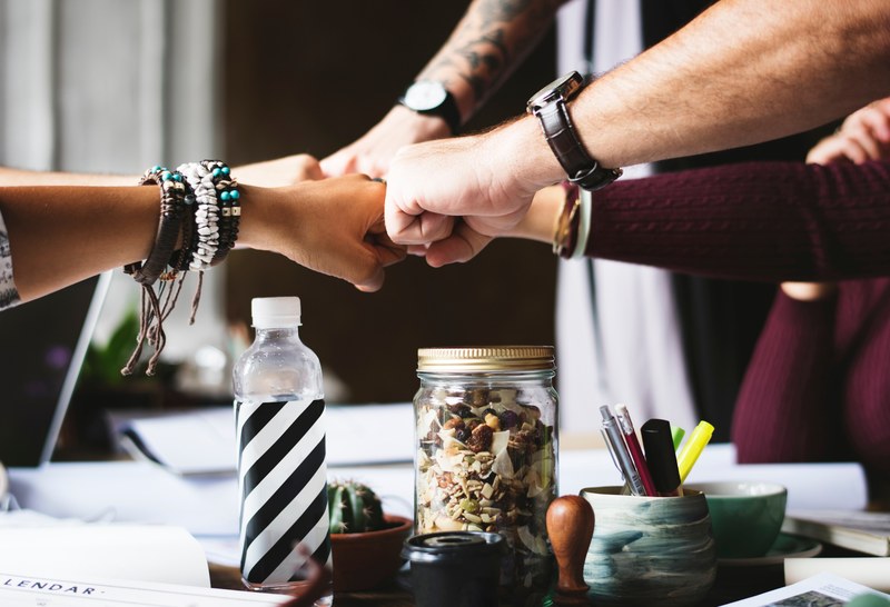several people fist bumping over a busy workspace, teamwork and friendship 4k