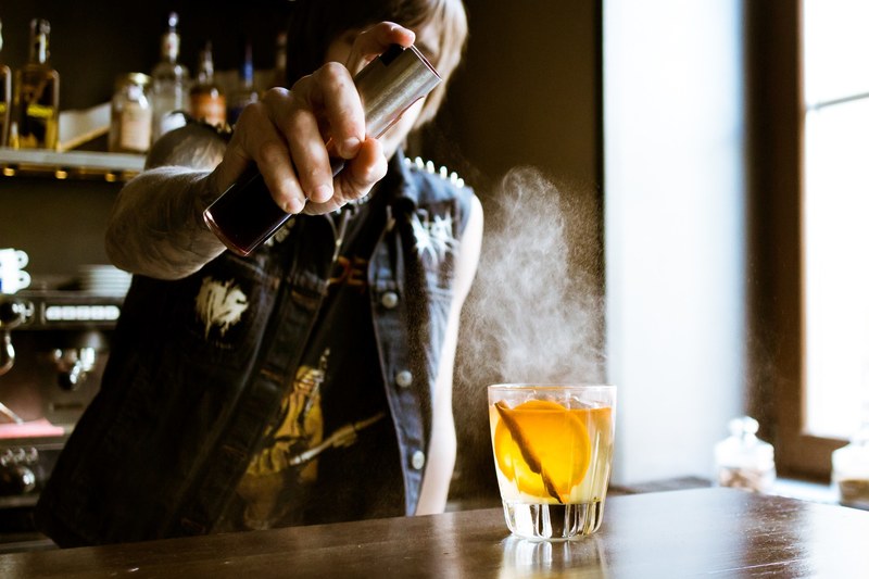 a bartender spraying an a whiskey drink with cocktail in a bar in vozdvyzhensky, bartender spraying on whiskey 4k