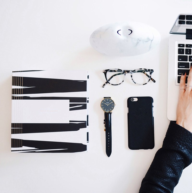 a flatlay image of a white desk with a laptop reading glasses a watch smartphone and various other items, _workspace essentials 4k