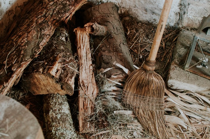 a broom leaning against a wall next to a disorderly heap of firewood, wormsloe 4k