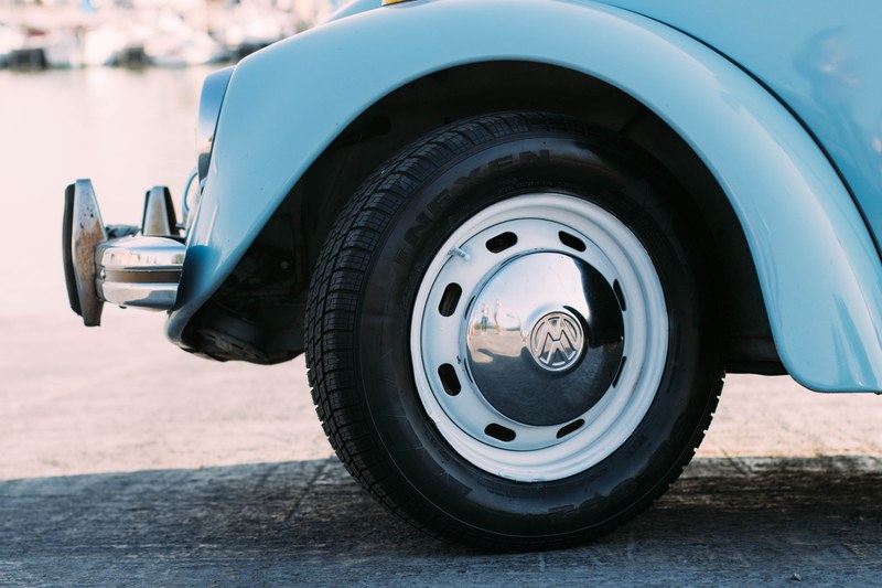front of volkswagen blue car with logo on hubcap, vintage volkswagen beetle 4k
