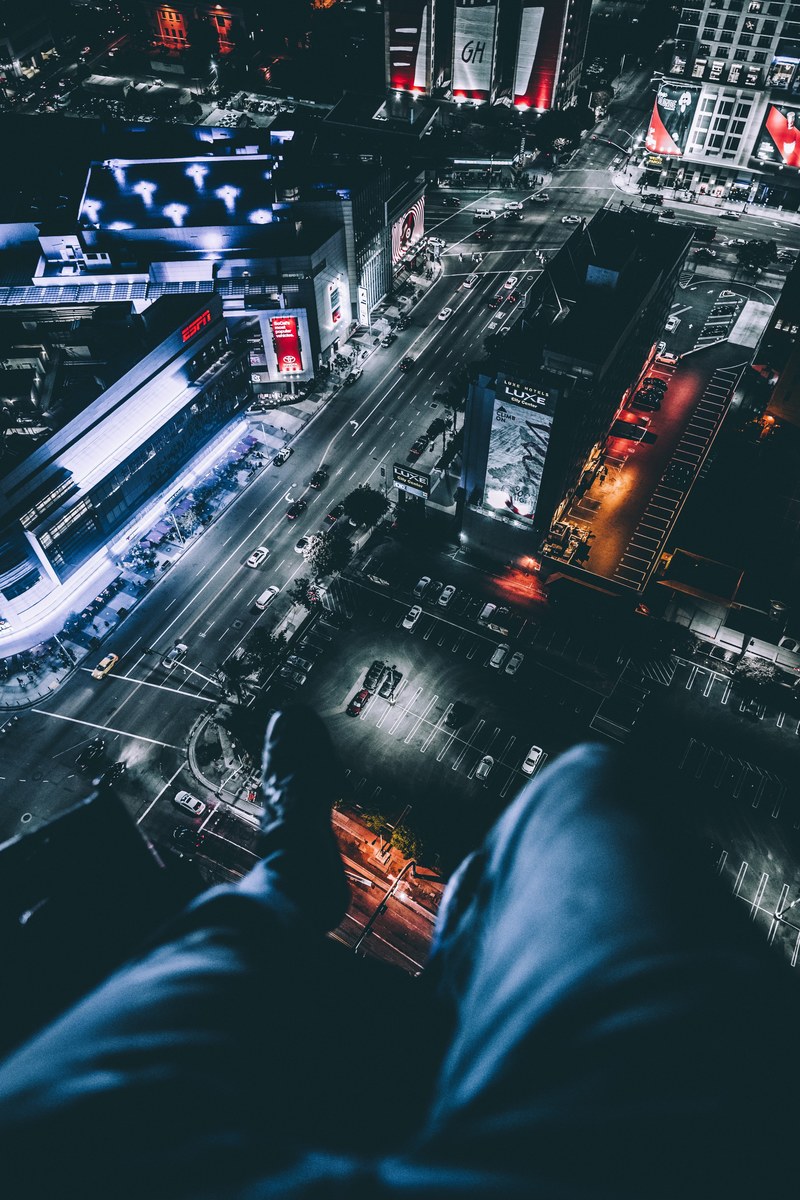 legs dangling off building roof looking at los angeles buildings and traffic, climbing high_ 4k