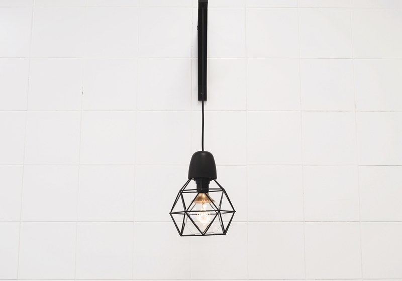 single geometric lantern with light bulb hanging on a white wall, geometric decor 4k