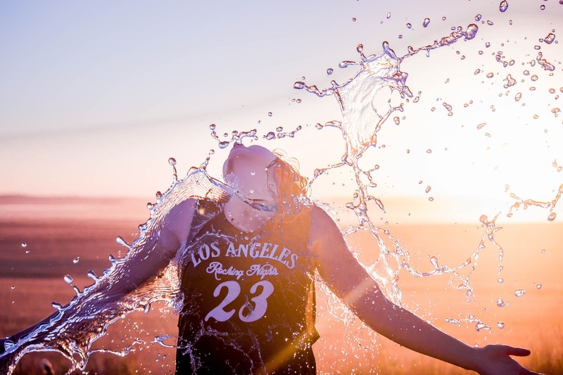 female wearing a los angeles jersey being splashed with water under the sunset in alberta, water refreshes athlete 4k