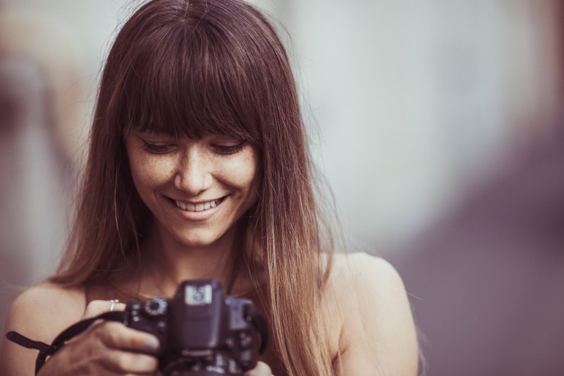 a woman with brown hair and bangs smiles town toward her camera against a blurry background, woman smiling at camera 4k