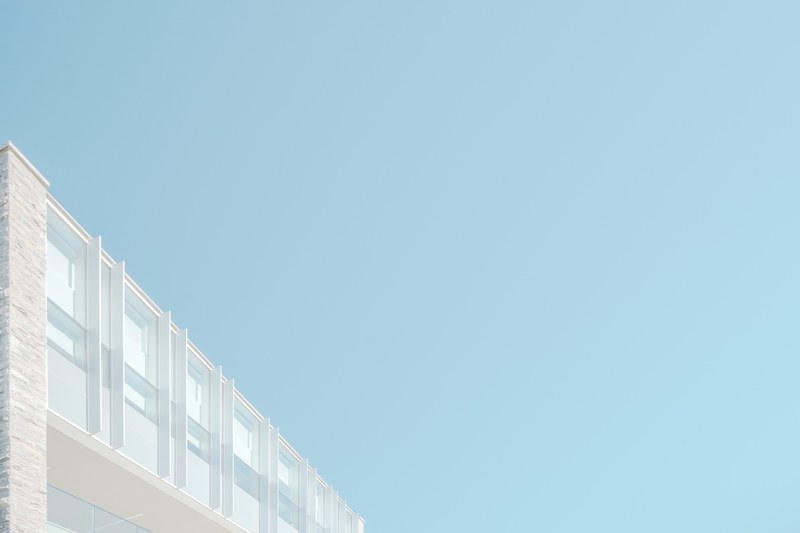 the top of a white modern facade under pastel blue sky, modern facade under blue sky 4k