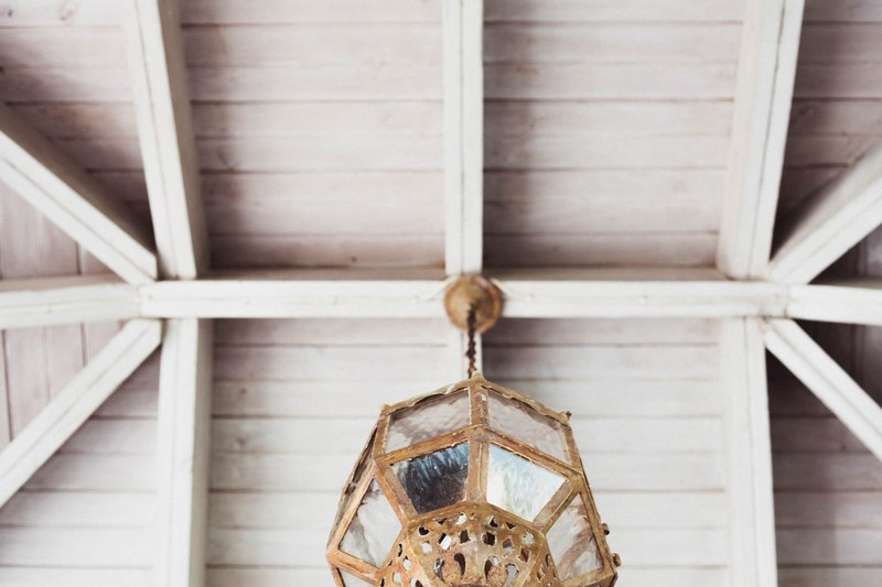 a white wooden beam ceiling with a vintage lamp hanging from it, light under the terrace 4k