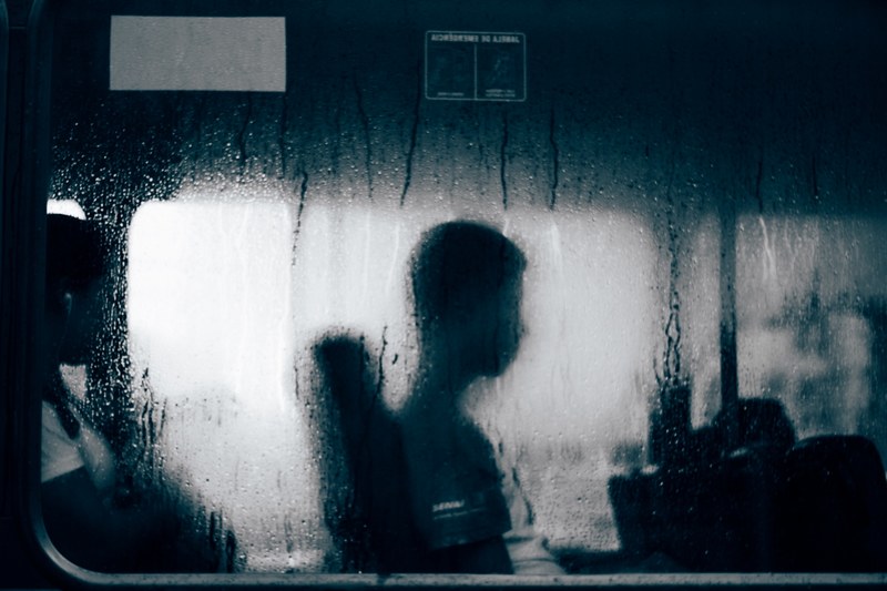 profile silhouette of person sitting near window with rain water on it, person sits near rain window 4k