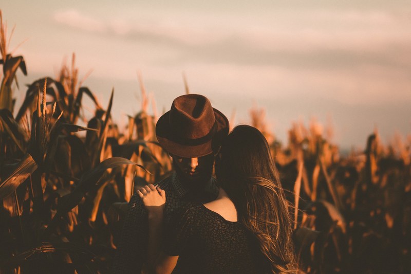 a man with a fedora is embracing a woman in a cornfield, _couple embracing in cornfield 4k