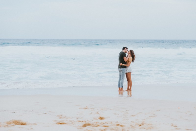 on bronte beach sea birds skim the surface while a man and a woman share tender moment, kiss on the beach 4k