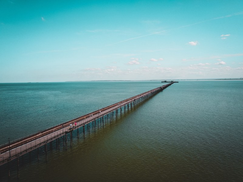 a drone shot of a walking bridge over the bay or ocean, walking bridge pier 4k