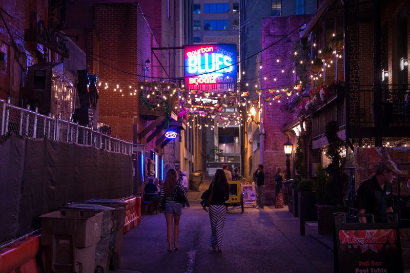 people walking through a downtown street under a line of lights, _printers alley 4k