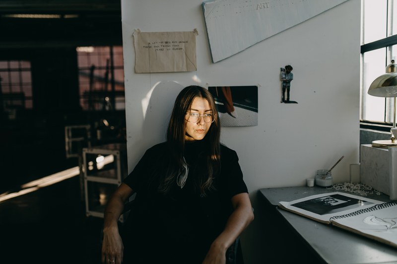 young attractive dark haired woman sitting and contemplating in art workshop in springfield, artist thinks in springfield 4k