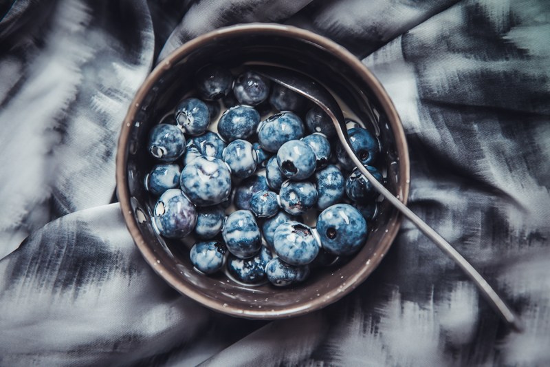 blueberries and milk in a bowl with a spoon on a bedsheet, childhood favourite dessert 4k