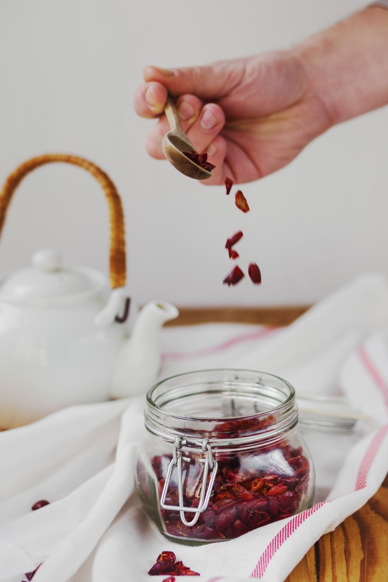 a person scooping out loose leaf tea to brew in a teapot, making rosehip tea 4k