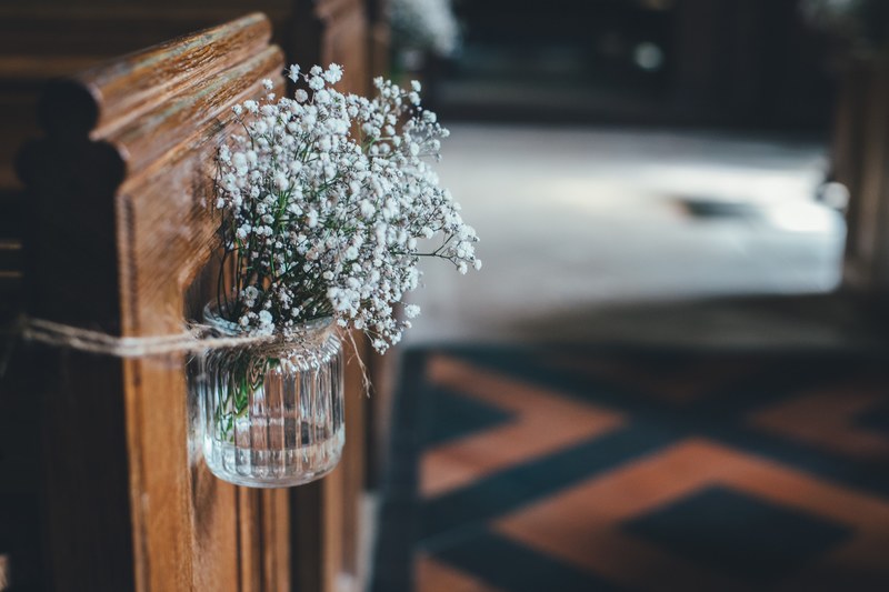 white babys breath flowers in a glass jar attached to a church pew, flowers in a church aisle 4k