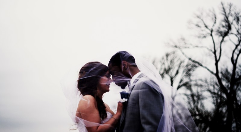 bride and groom stand under the veil outside, making smiles together 4k