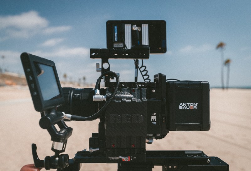 red recording camera with monitor display filming a beach setting, beach bae 4k