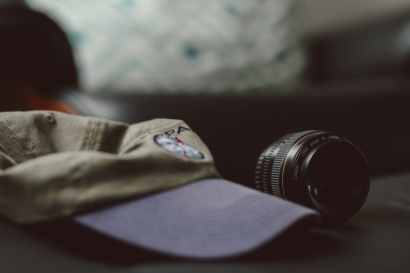 a cap beside a dslr canon lens, camera lens and baseball cap 4k