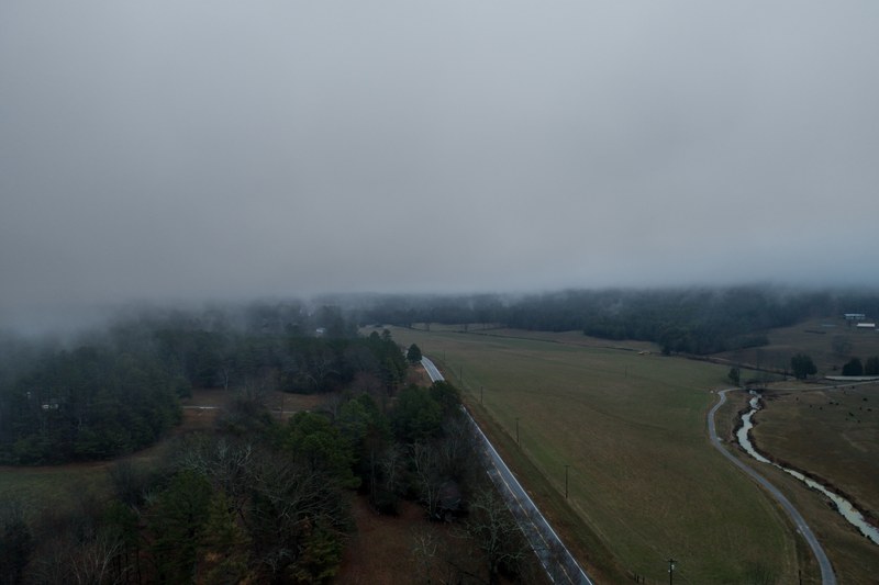 aerial drone shot of rural fields and trees on a foggy day, rural roads from above 4k