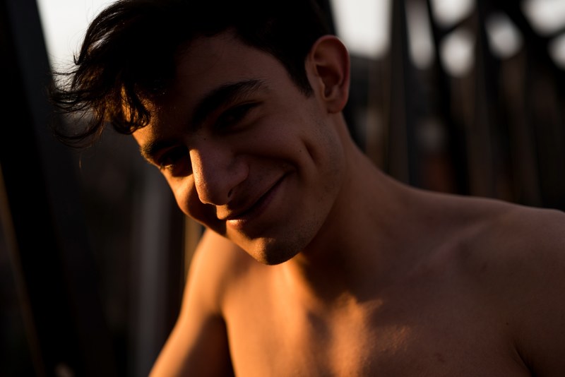 a shirtless man with dimples smiles as shadows fall across him, shadows fall on dimpled man 4k