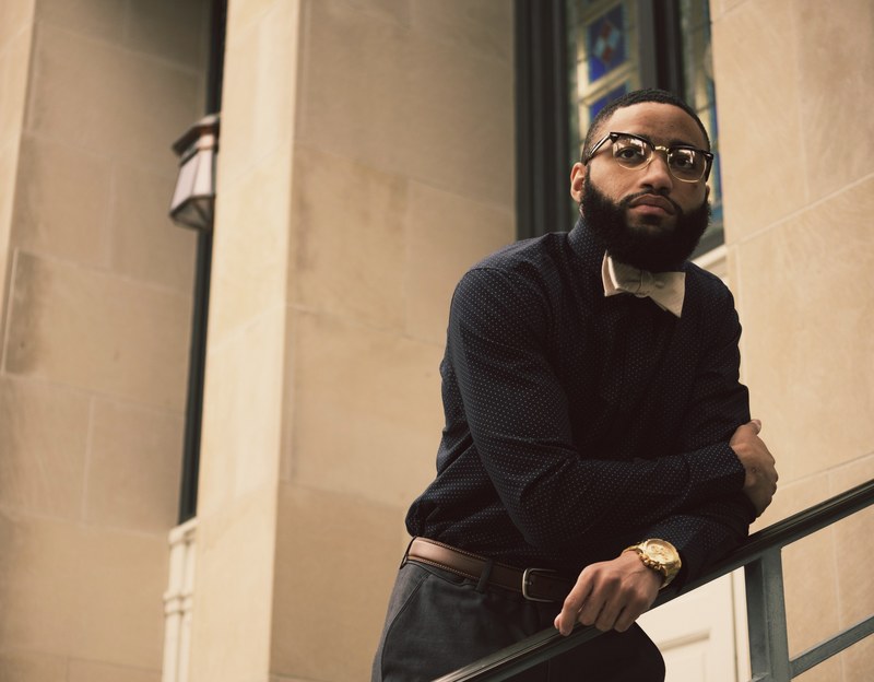 trendy man in a bowtie leans against a building railing, professional bowtie 4k
