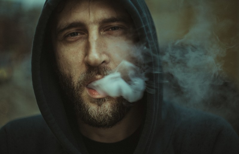 man in a hoodie exhaling smoke from his mouth, smoky exhale 4k