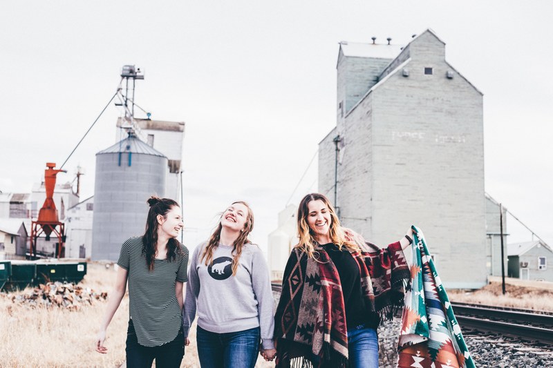 a group of three friends laughs alongside train tracks holding blankets in texas, three friends by train tracks 4k
