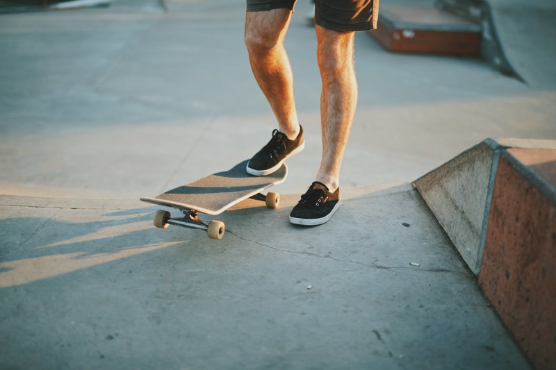 a man wearing sneakers is stepping on a skateboard at a skatepark in cherrybrook, _man and skateboard at dusk 4k