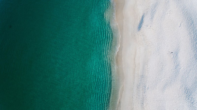 drone view of a clear ocean washing up on sand shore in nelson bay, drone view of ocean waves 4k