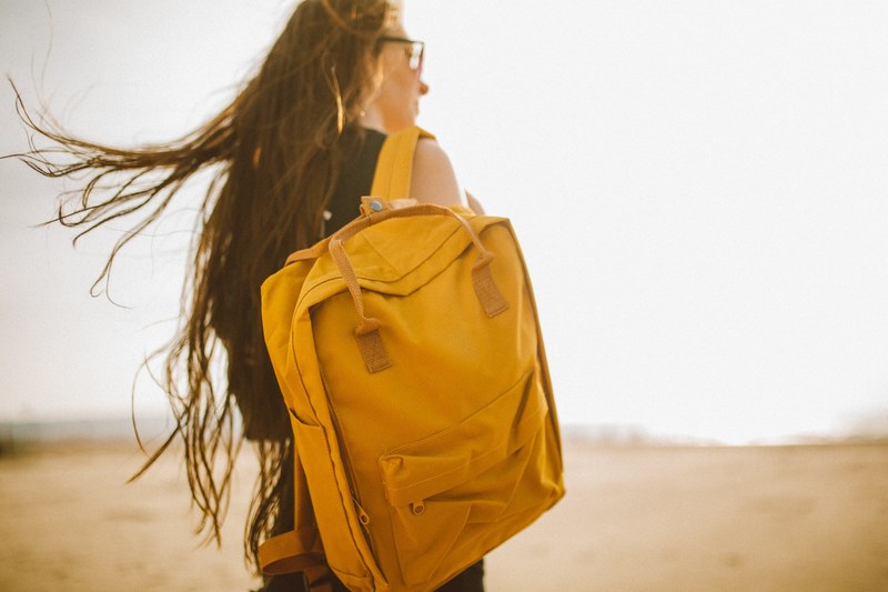 a woman carrying a yellow backpack on her back in weston super mare, weston super mare backpack 4k
