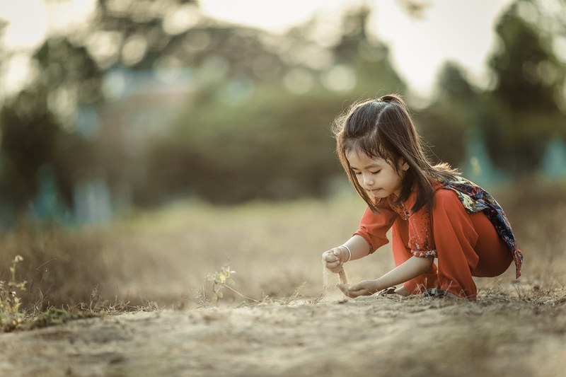 a little girl wearing orange red playing in the sand in cao lnh, cao lnh sandbox 4k