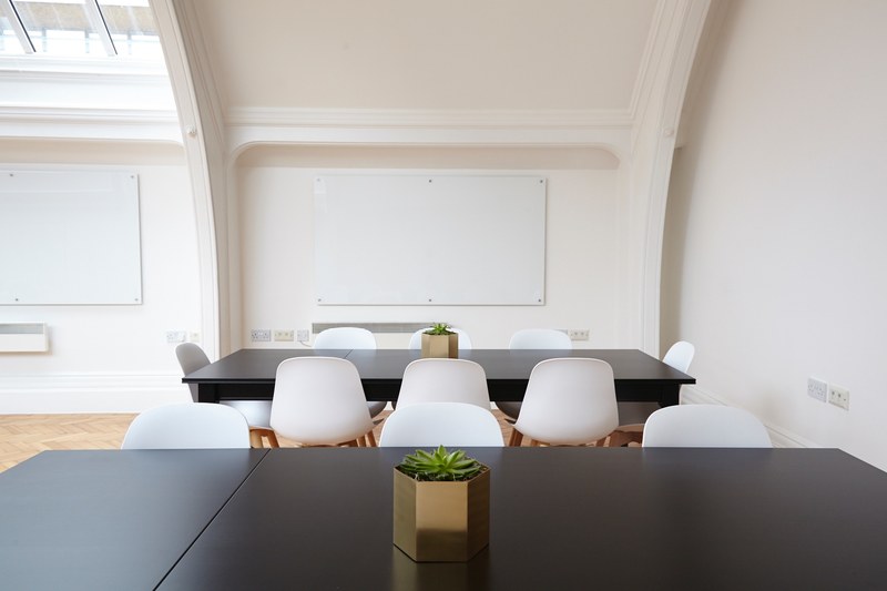 an elegant conference room with two whiteboards black tables and white chairs, white and black office space 4k